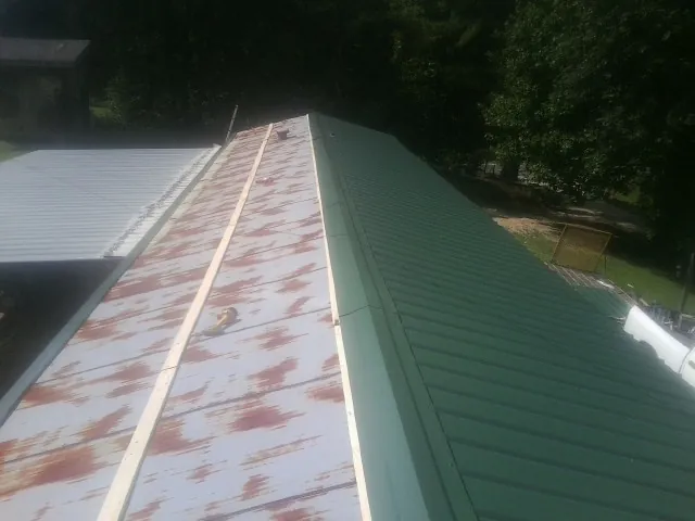 Old rusted panels beside newly installed green metal roofing — Wind Damage Roof Repair by Roofing Brothers in Pomfret