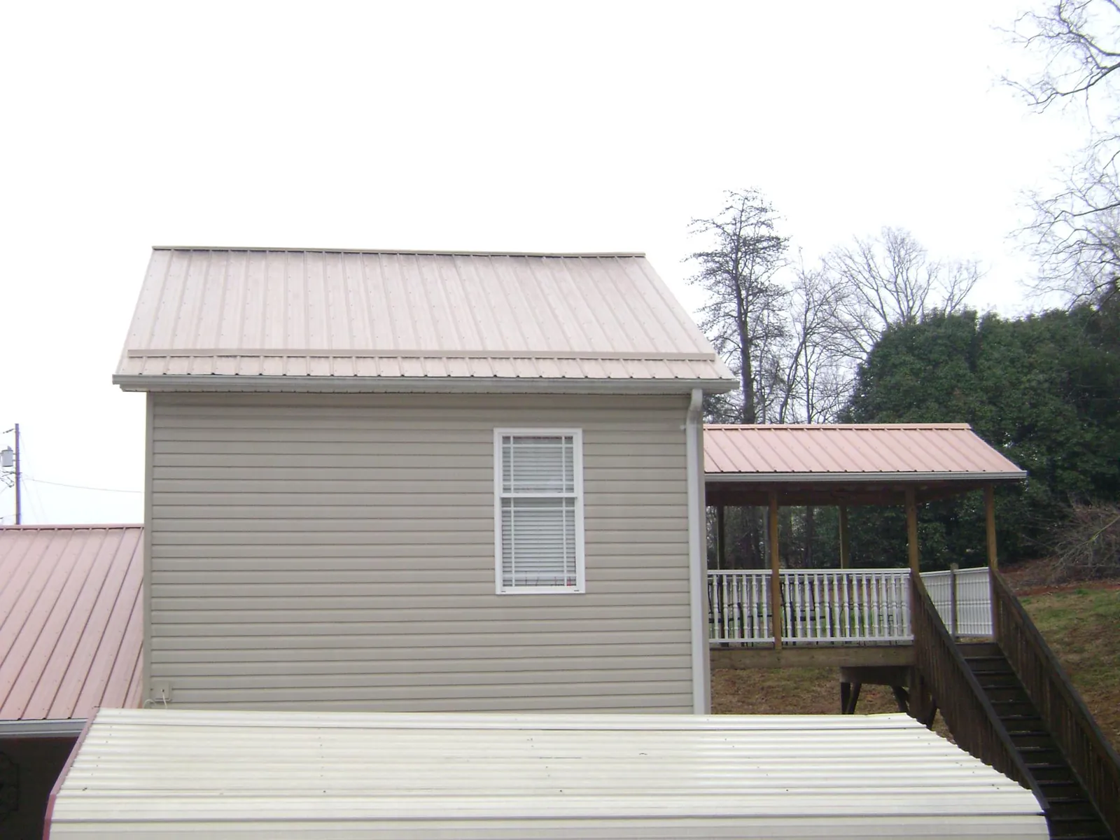 Tan metal roofs on a two story addition and attached porch, from a Roof Replacement job in Pomfret