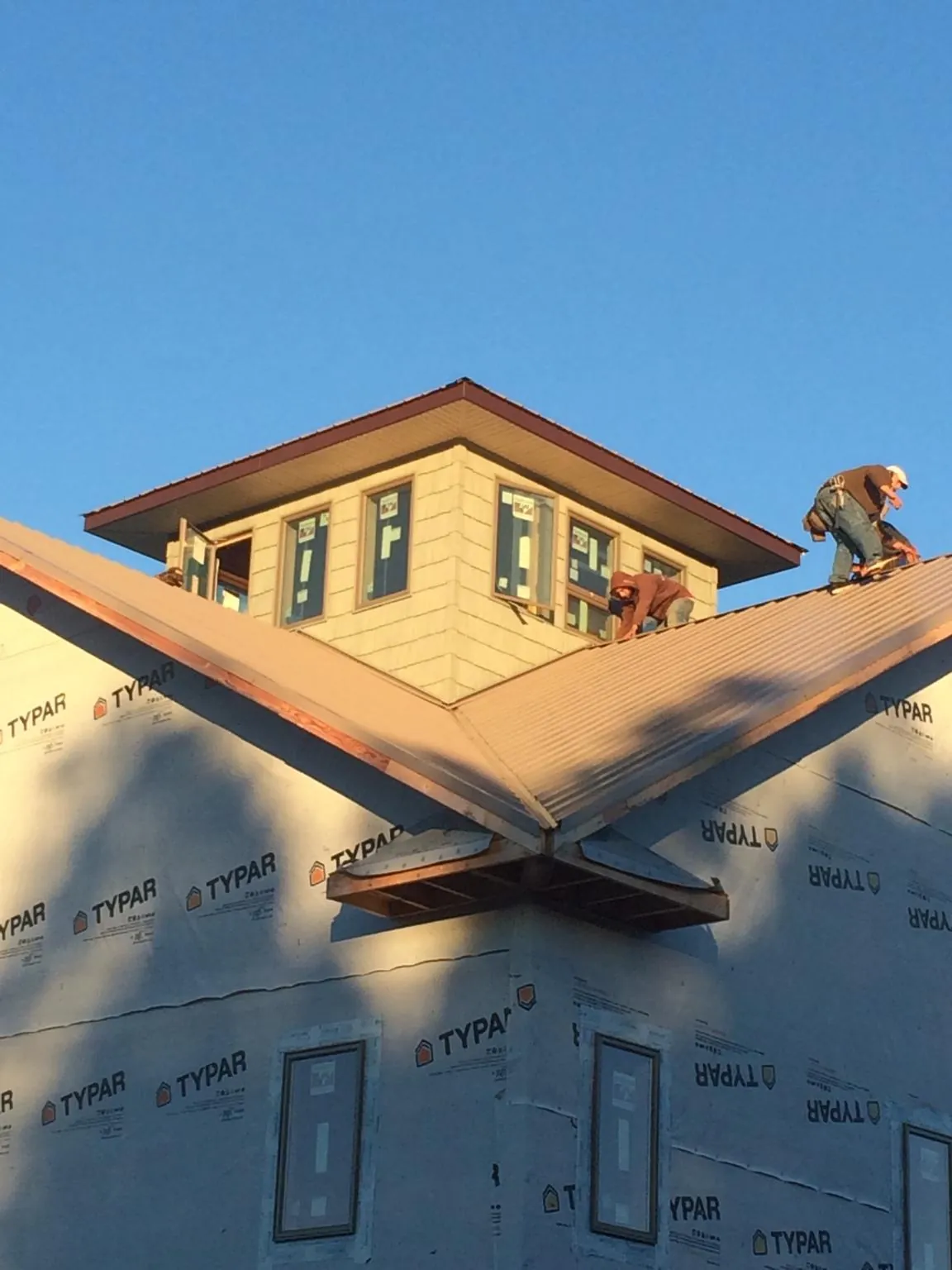 Roofers working around a rooftop cupola on a new metal roof at sunset — Roof Waterproofing in Pomfret by Roofing Brothers